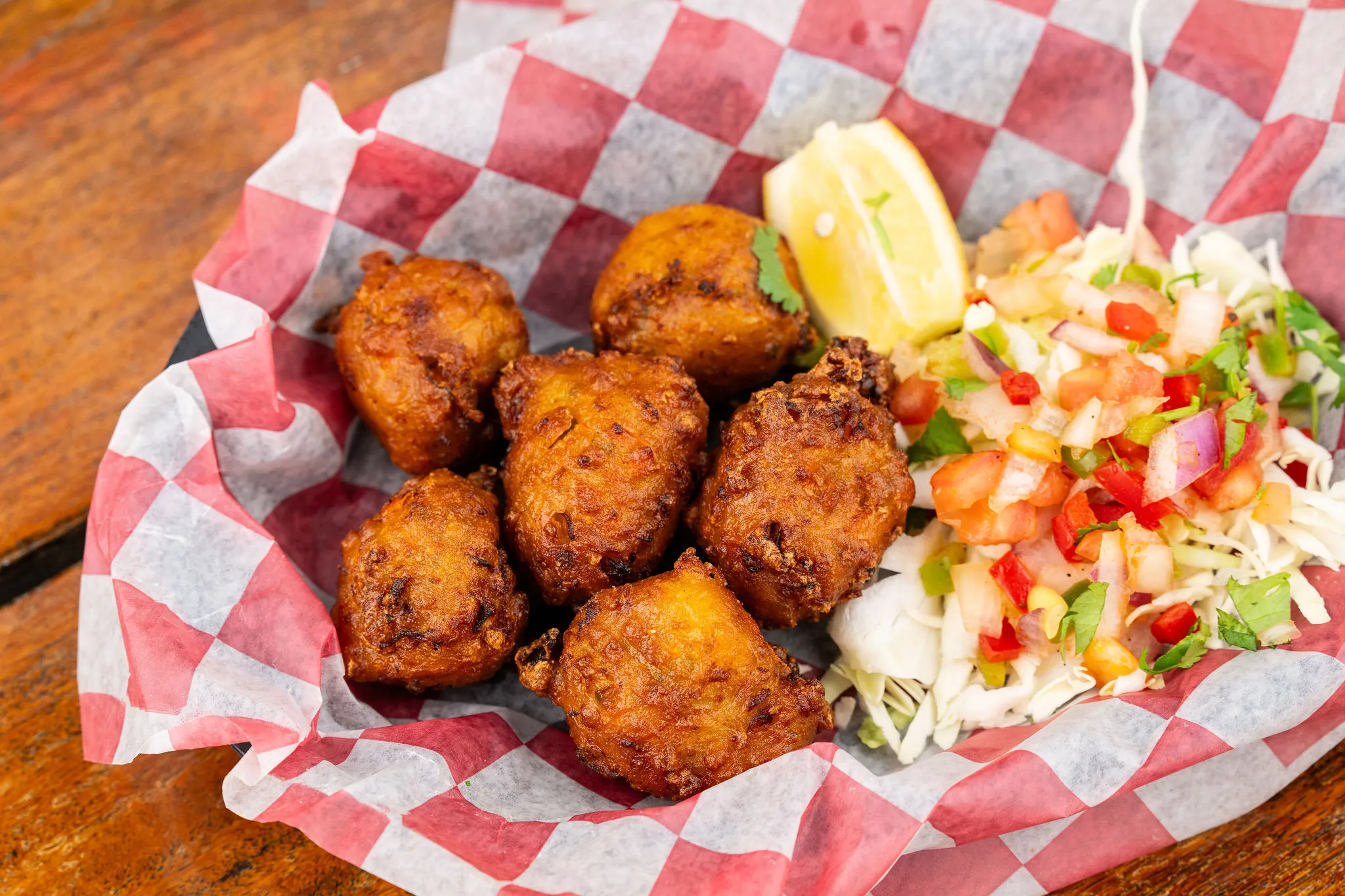 A basket of golden conch fritters with coleslaw and a lemon wedge at Hogfish Bar & Grill