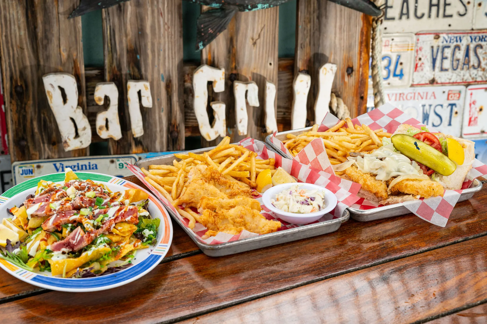 Fried hogfish, a fried hogfish sandwich, and tuna nachos on trays at Hogfish Bar & Grill